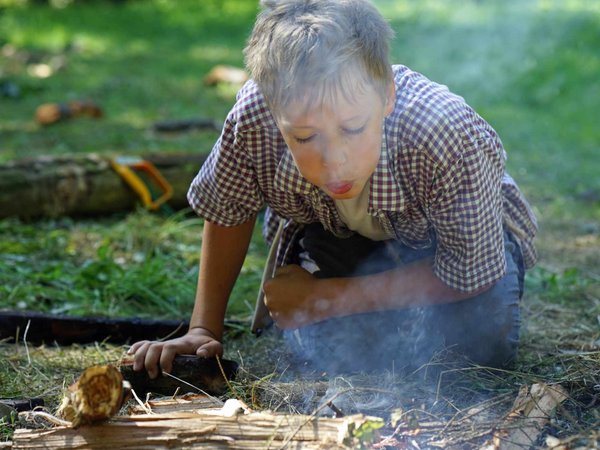 Bei der Ferienaktion "Leben in der Steinzeit" rund um die Luisenhütte in Balve-Wocklum lernen die Kinder unter Aufsicht auch wie sie mit einem Feuerstein ein Feuer entfachen können. Foto: Stephan Sensen/Märkischer Kreis