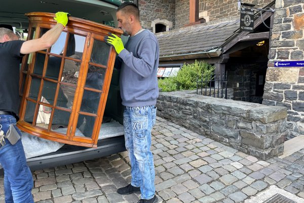 Die Museumstechniker der Burg Altena transportieren den Glasaufsatz eines Biedermeierschranks in die Räume der Sonderausstellung. Foto: Bernadette Lange