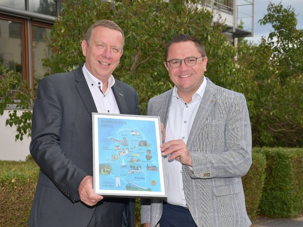 Ausflugstipps aus dem Märkischen Kreis: Landrat Marco Voge (r.) überreichte seinem Gastgeber aus dem Landkreis Elbe-Elster, Landrat Christian Jaschinski (l.), eine gerahmte Kartenübersicht zu sehenswerten Ausflugszielen im Märkischen Kreis. Fotos Pressestelle Elbe-Elster 