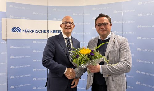 Der amtierende Landrat Marco Voge (rechts im Bild) überreicht dem zukünftigen Landrat Ralf Schwarzkopf einen Blumenstrauß. Foto: Alexander Bange / Märkischer Kreis