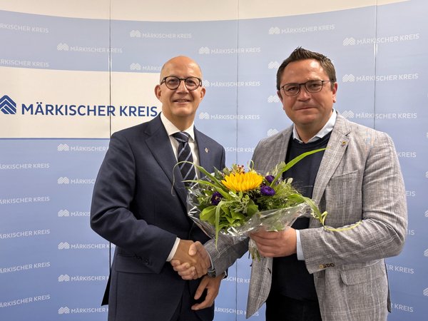 Der amtierende Landrat Marco Voge (rechts im Bild) überreicht dem zukünftigen Landrat Ralf Schwarzkopf einen Blumenstrauß. Foto: Alexander Bange / Märkischer Kreis